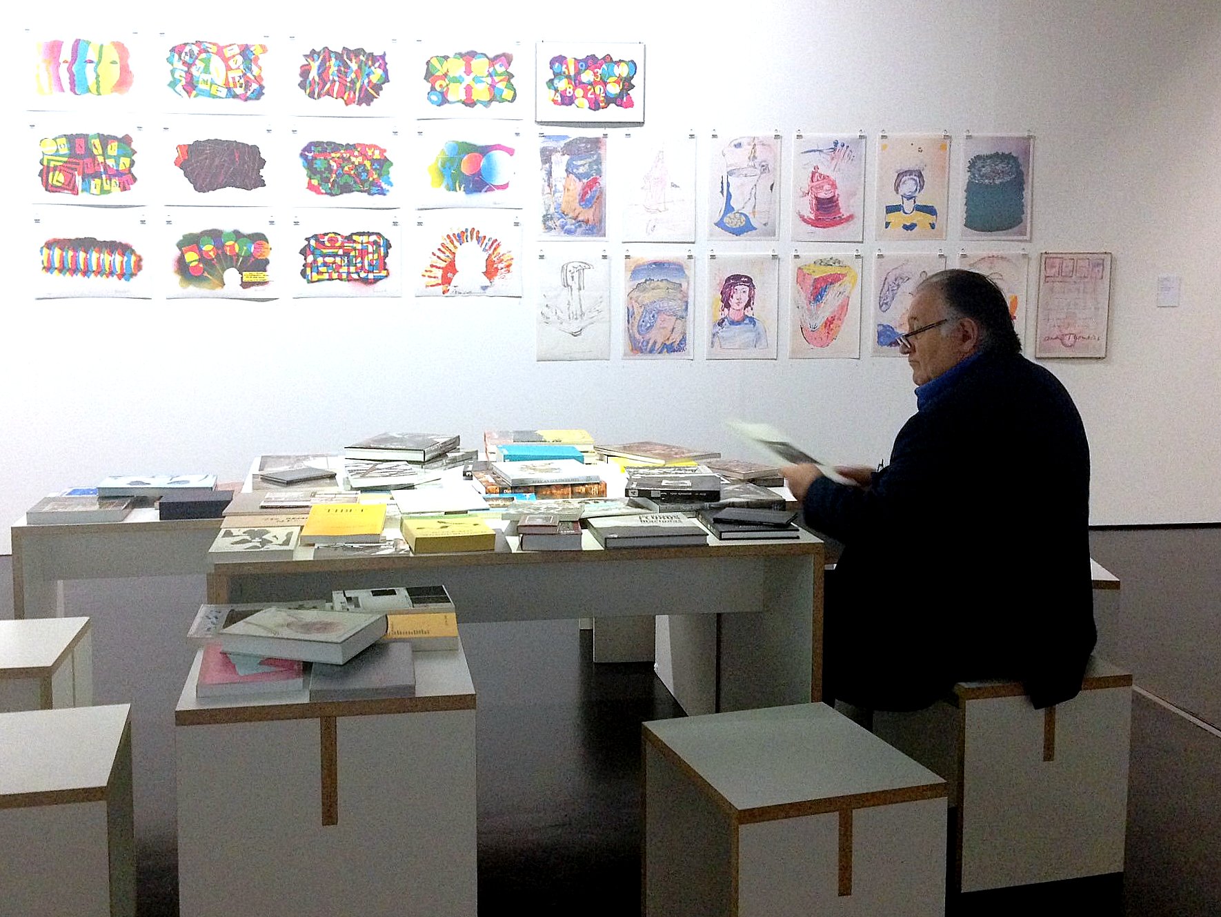 Peter Weibel sitzt im ZKM an einem Tisch mit Büchern