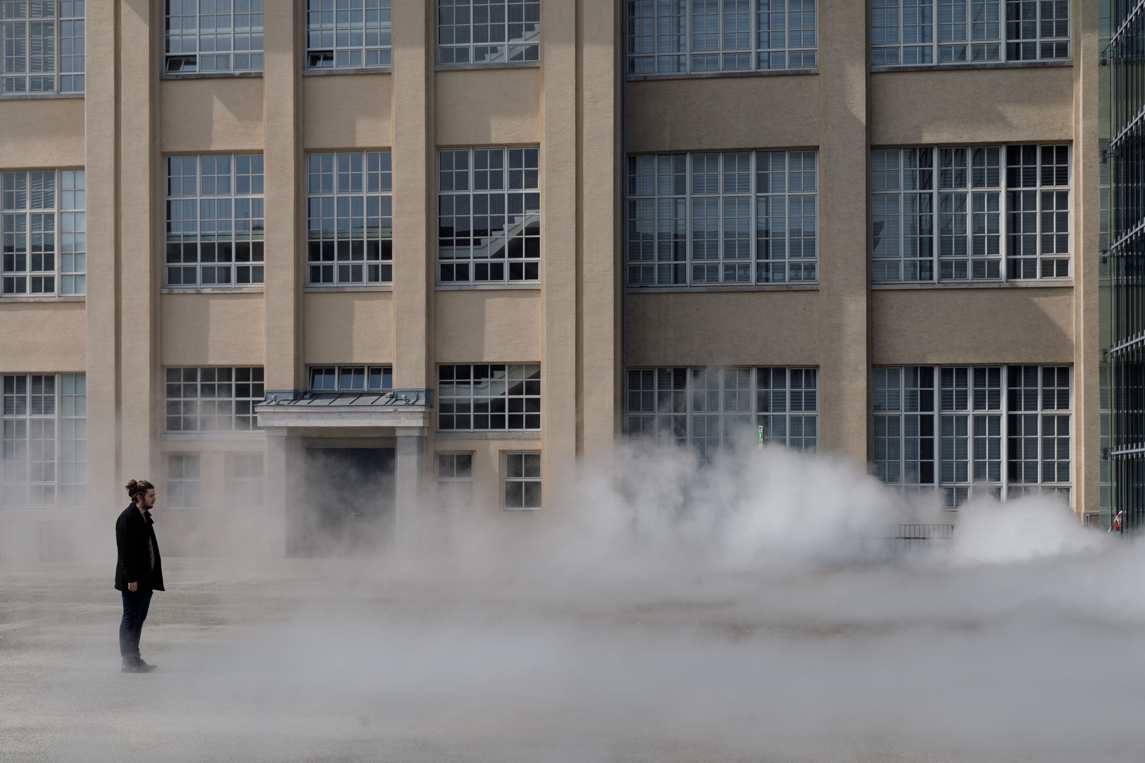 Das Foto zeigt einen Mann ummantelt von der Nebelskulptur der japanischen Künstlerin Fujiko Nakaya. Im Hintergrund ist die Fassade der alten Munitionsfabrik zu sehen.