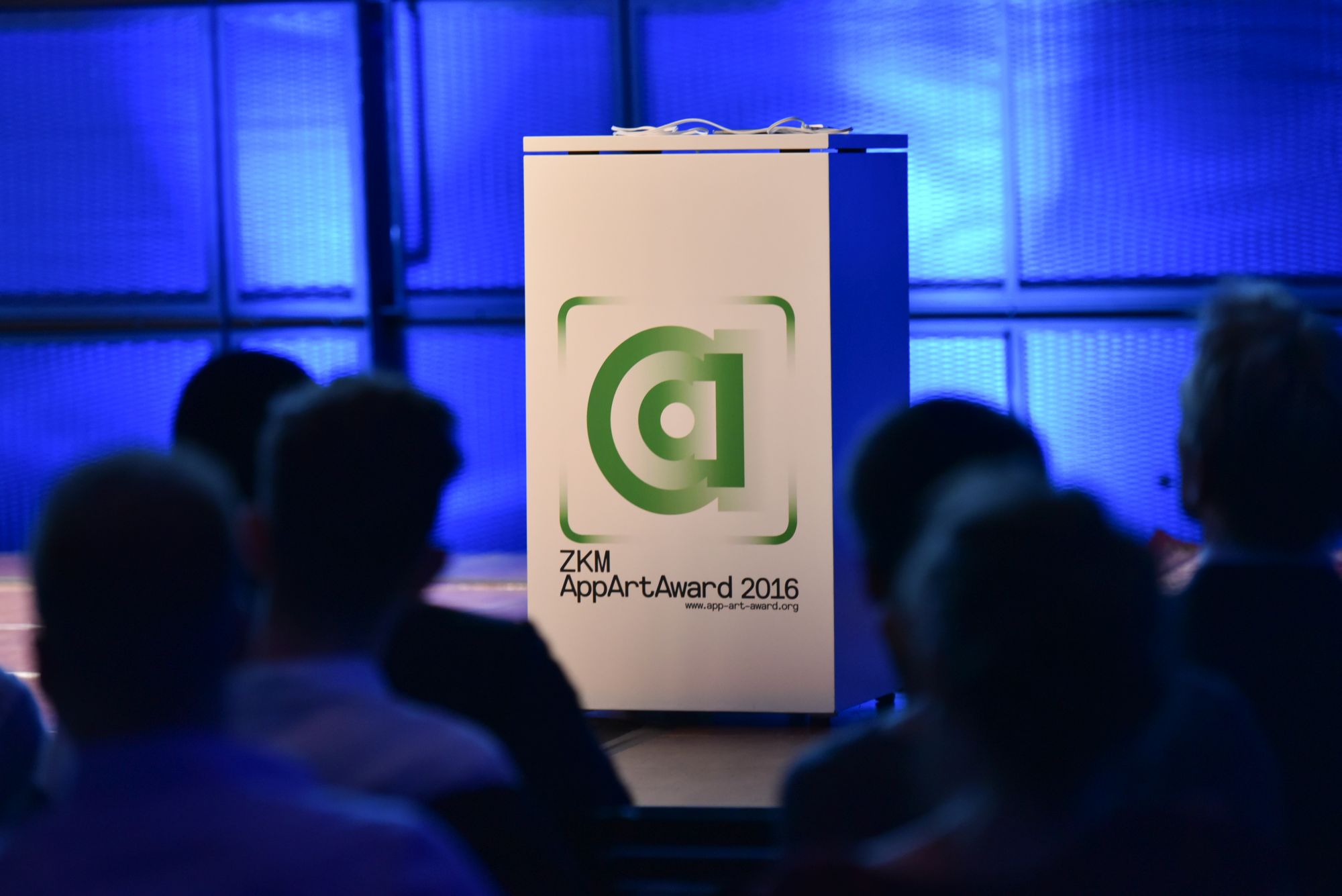 Blick durch das Publikum auf das Rednerpodest des AppArtAward