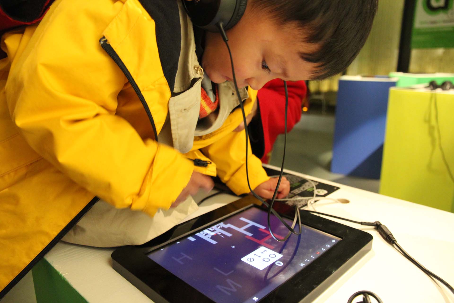  A little Chinese boy is bent over a Ipad.