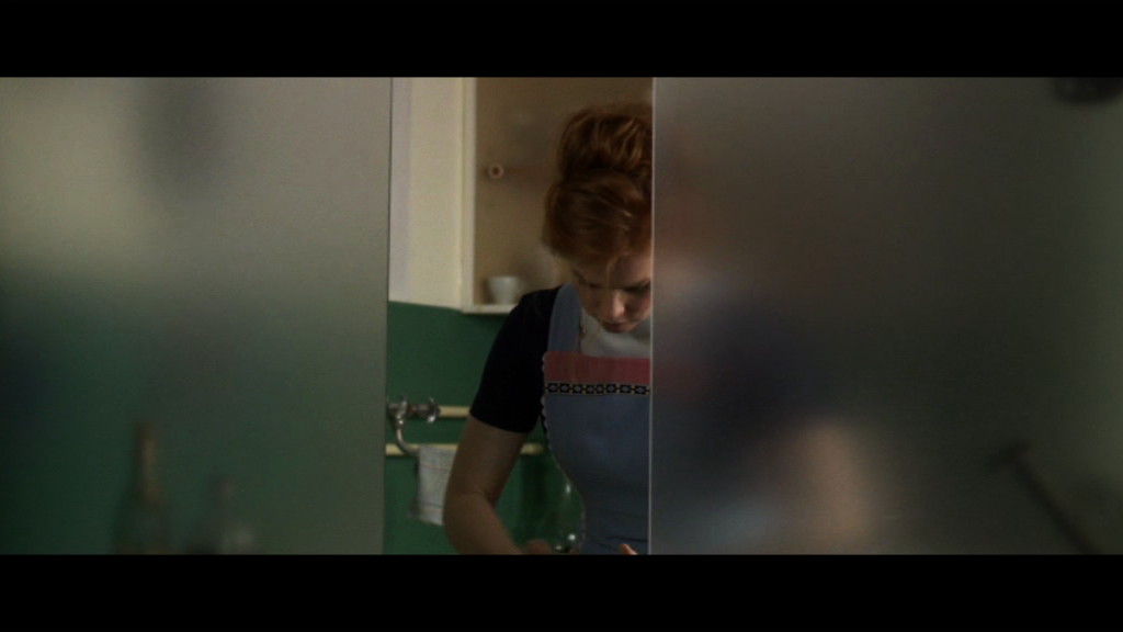 Eine Frau in der Küche hinter einer Scheibe