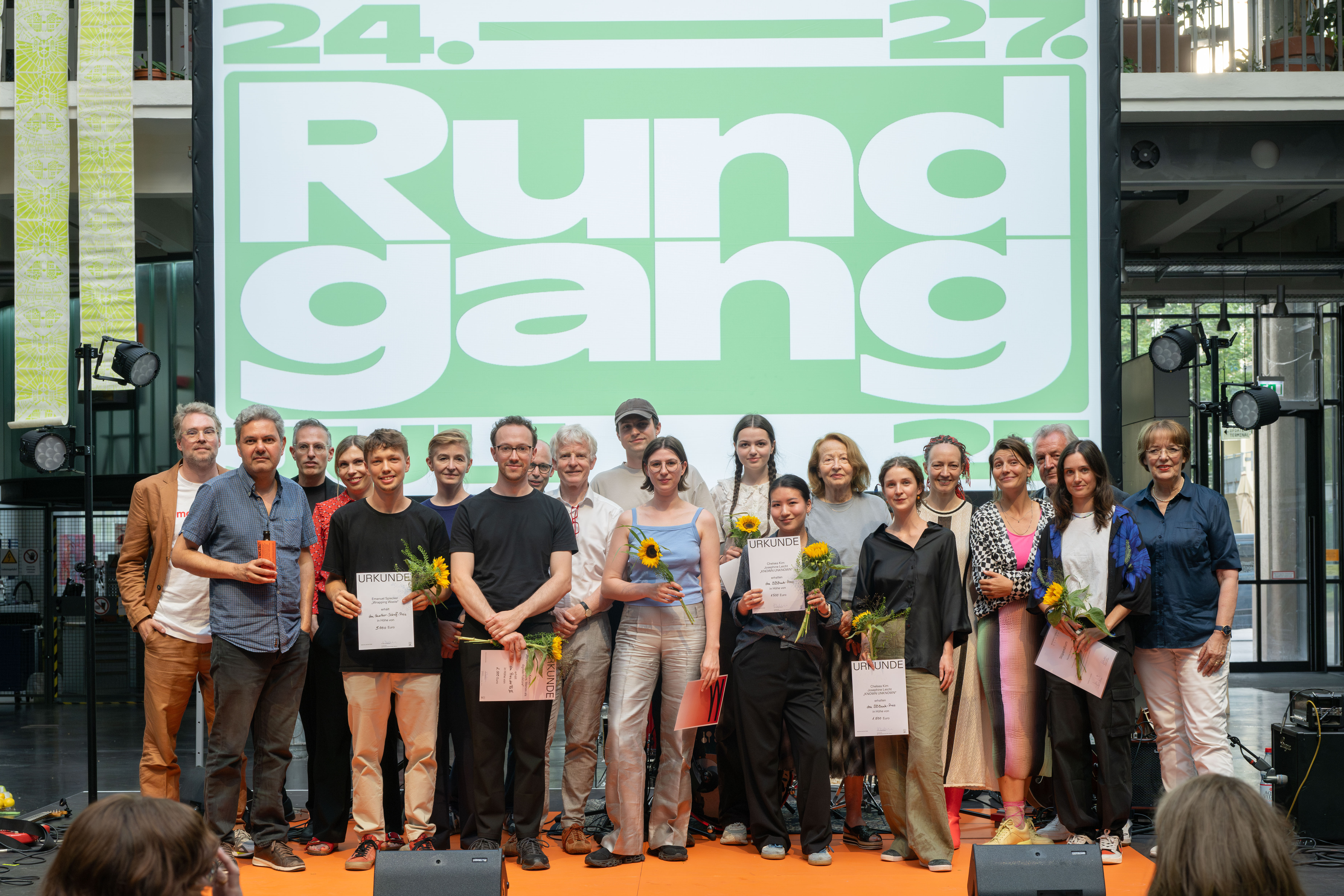 Several people (the jury and the award winners) can be seen on a stage.