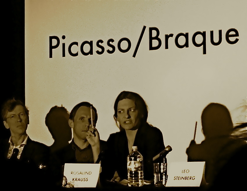 Von links nach rechts: Zwei Männer und eine Frau an einem Tisch. Sie redet und hält dabei einen Bleistift in ihrer rechten Hand. Auf dem Tisch stehen Namensschilder. Im Hintergrund ist 'Picasso/Braque' zu lesen.