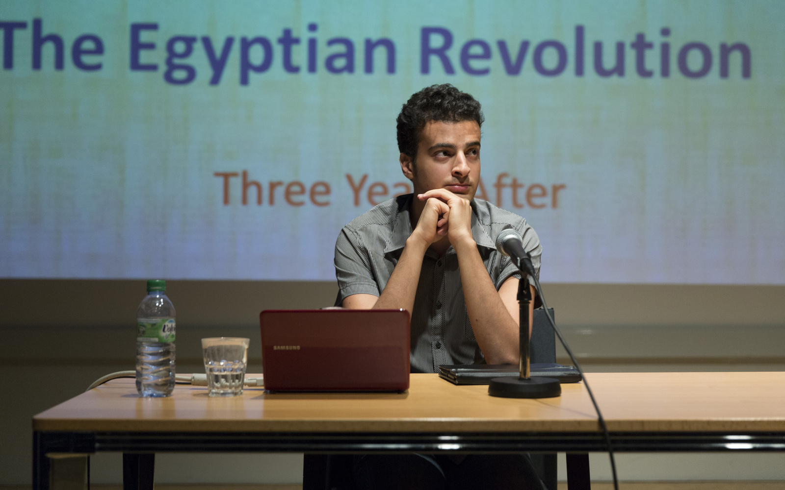 Two man sitting at a table with a laptop and a microphone