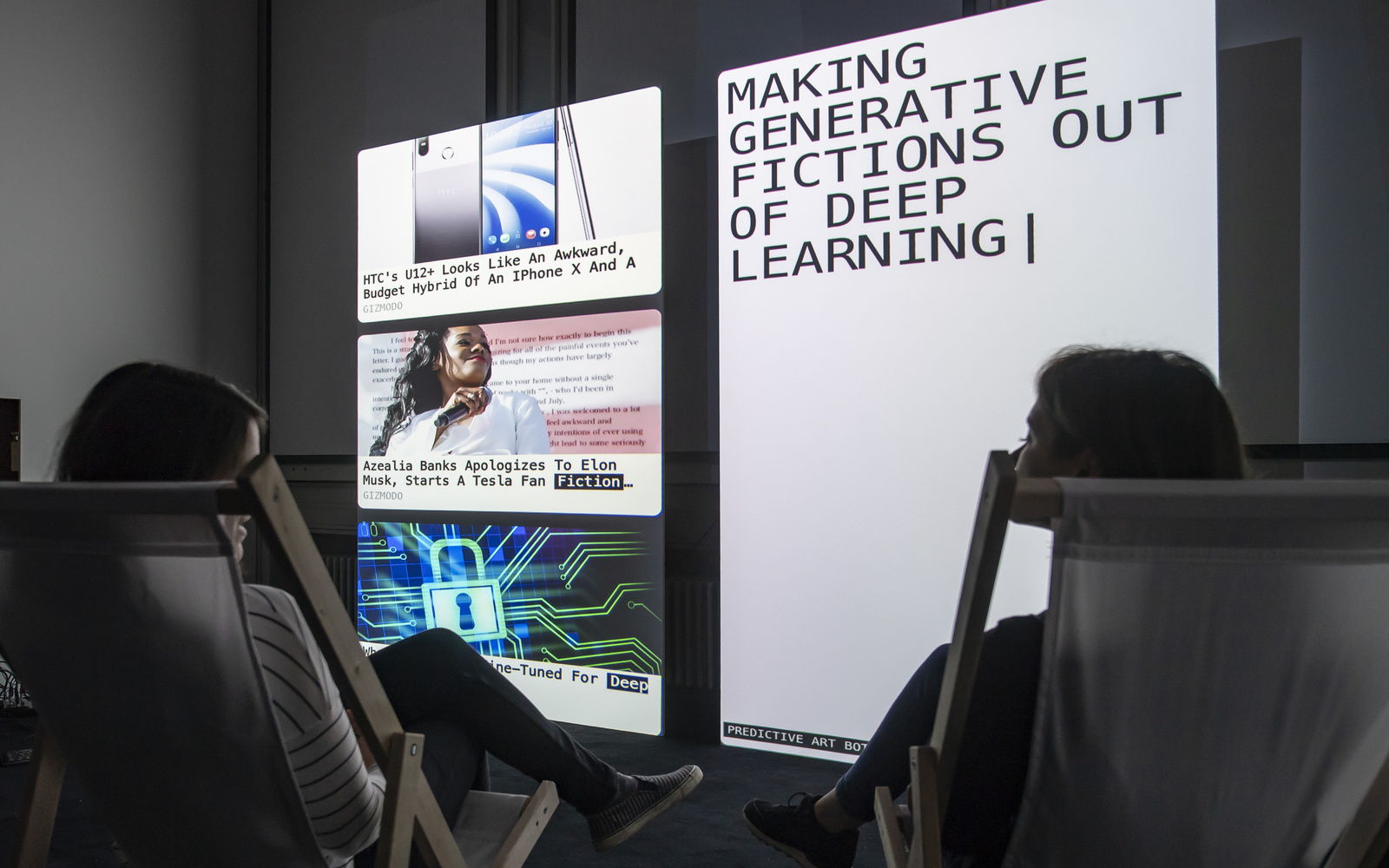 Two people sit in deck chairs in front of two large screens. On the right screen is written "Making generative fictions out of deep learning".