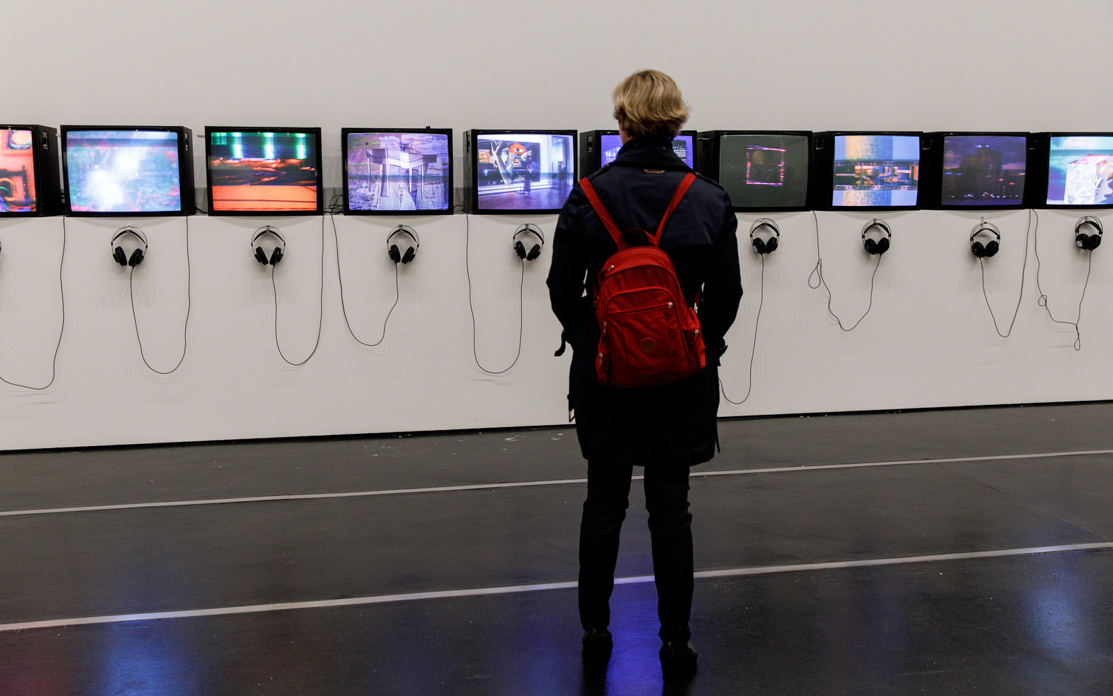 A woman is standing in front of a row of tube screens.