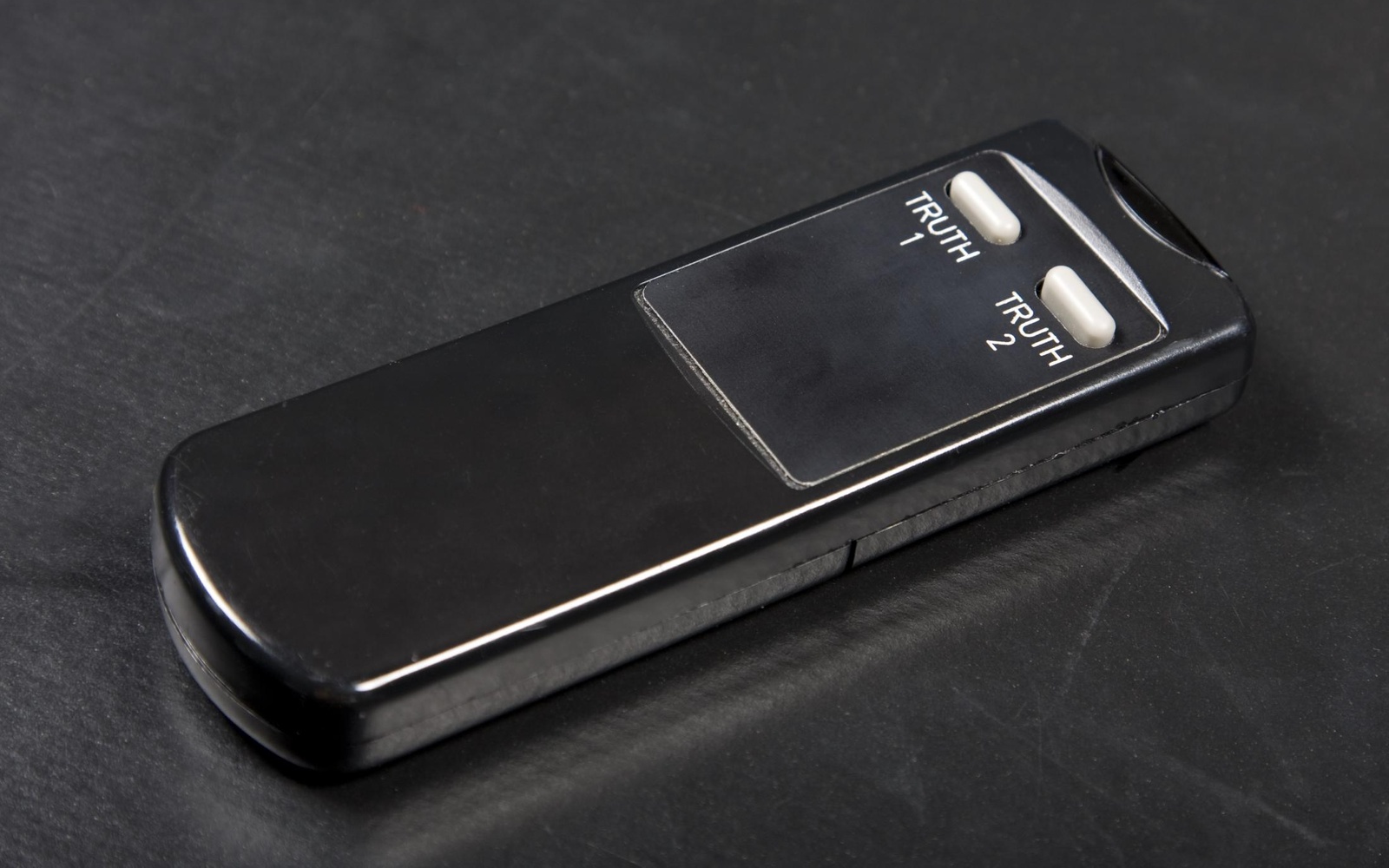 Illustration of a black remote control with the keyboards »Truth 1« and »Truth2«