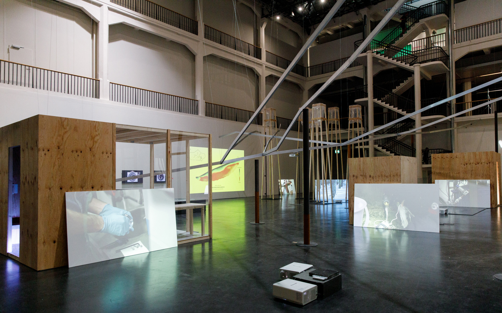 View into a large hall with a scaffolding and white walls on which videos are shown.