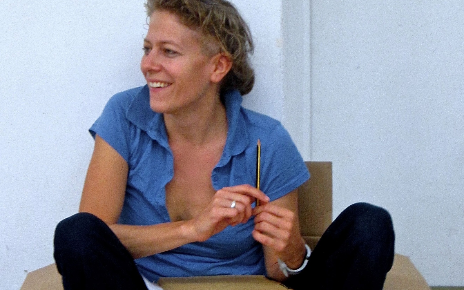  Anja Konjetzky sits casually in a cardboard box and holds a pencil in her hand.