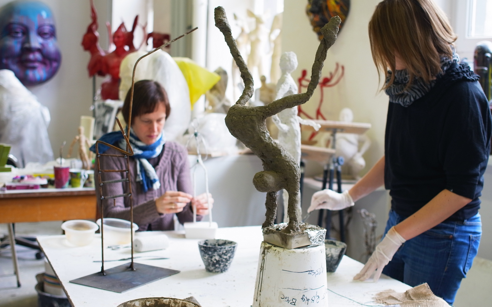 Frauen im Atelier arbeiten an schlanken Figuren aus Gips.