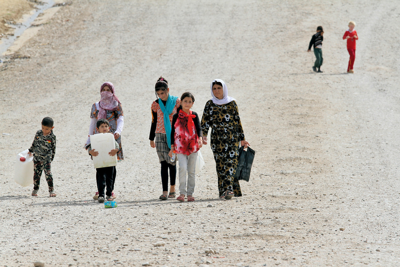 Junge verschleierte Frauen und Kinder auf einer Straße. 