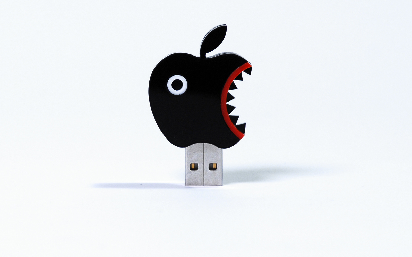 The photo shows a USB stick in the form of a black PacMan-like apple icon.