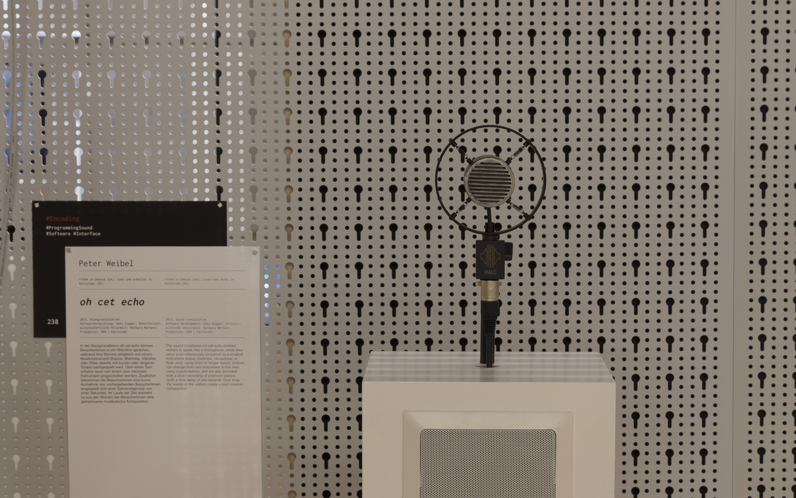 An old carbon microphone on a white pedestal.