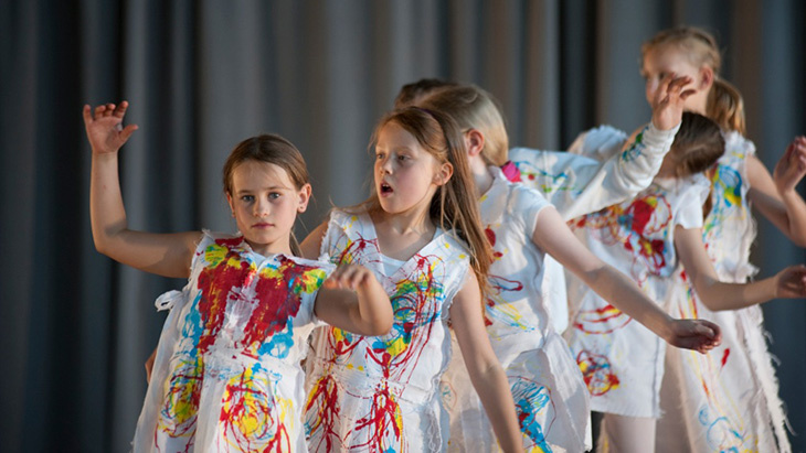 Children in colored gowns are dancing