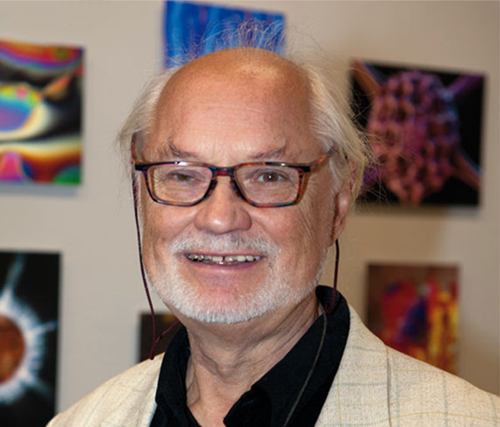 The artist Manfred P. Kage standing in front of hist photographic artworks.