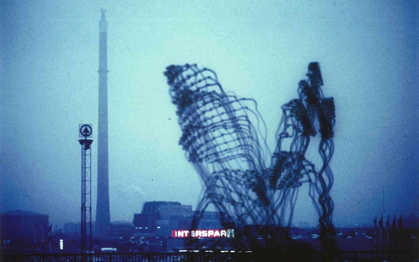 »Imaginäre Architekturen« von Otto Beckmann. Zu sehen ist eine trübe Skyline. Zwei große, figürliche Architekturen bilden das Hauptmerkmal. 