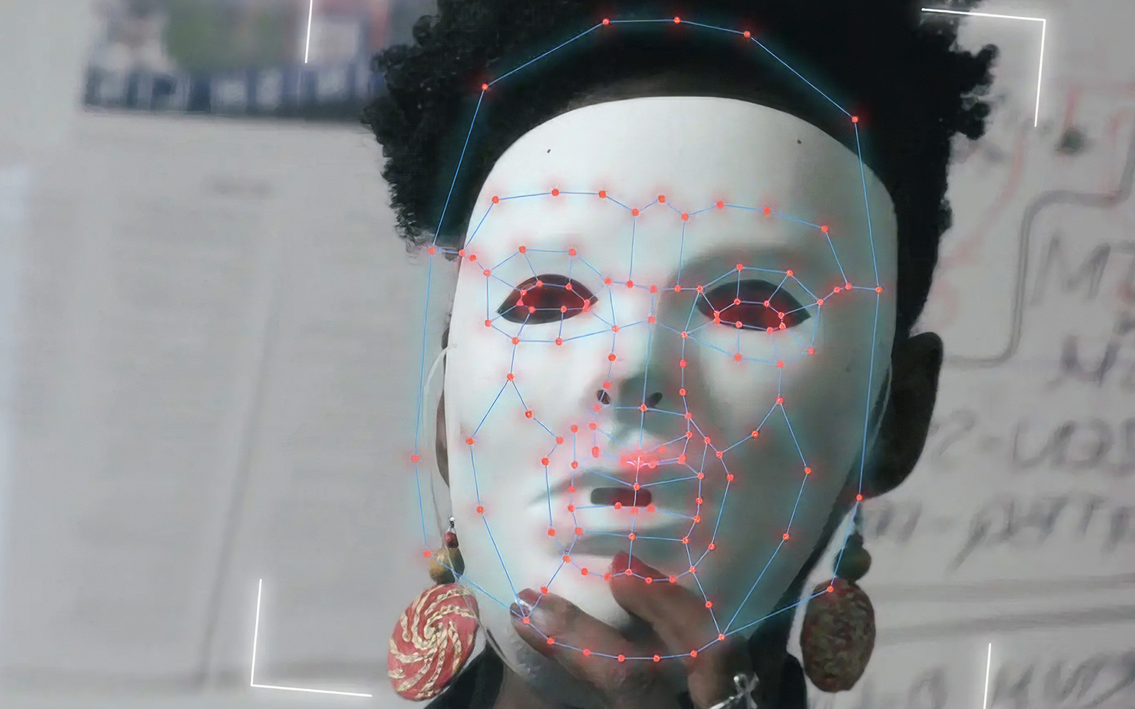 Eine schwarze Frau mit weißer Maske vor dem Gesicht. Die Maske scheint gerade von einem Computer gescannt zu werden.
