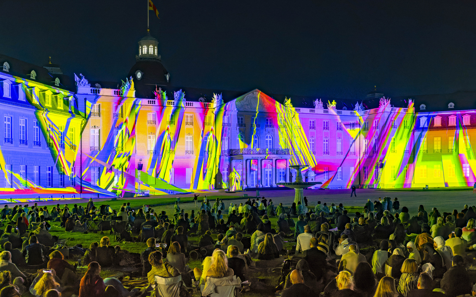 The picture shows the facade of the Karlsruhe Palace, onto which a show is being projected.