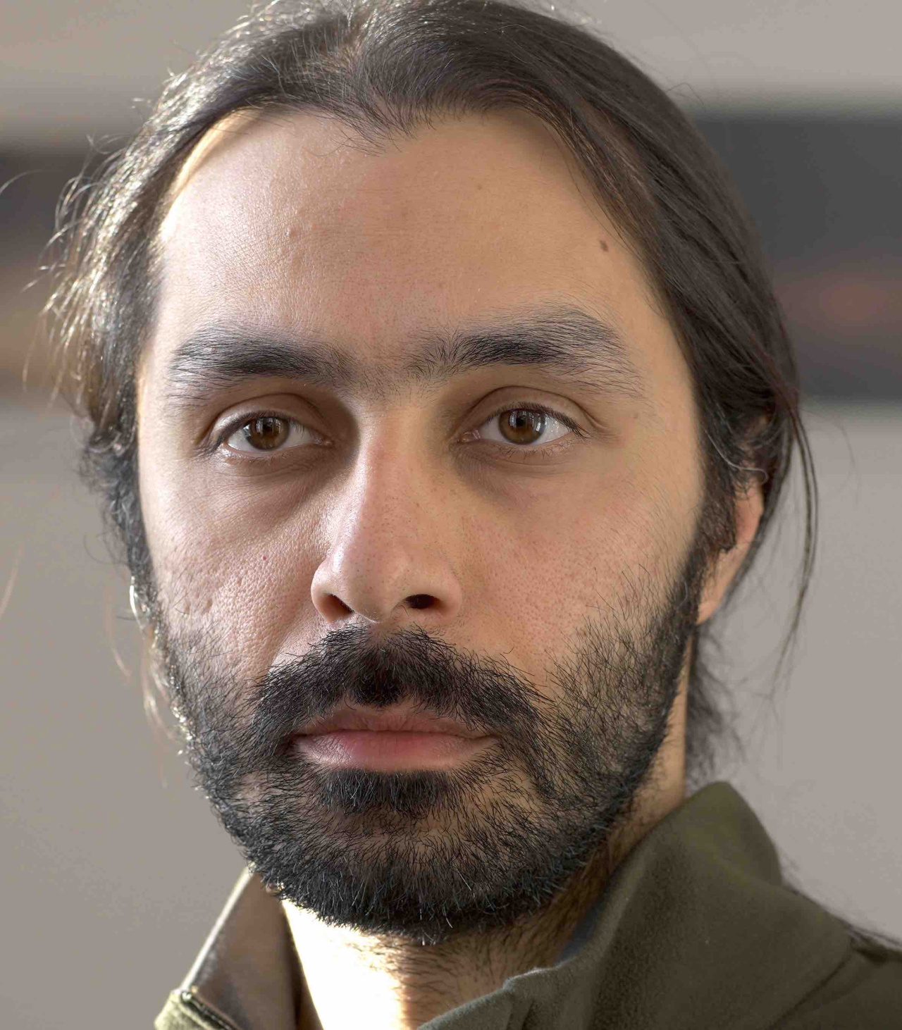 It is a portrait of a man with a beard and long hair, tied in a braid. 