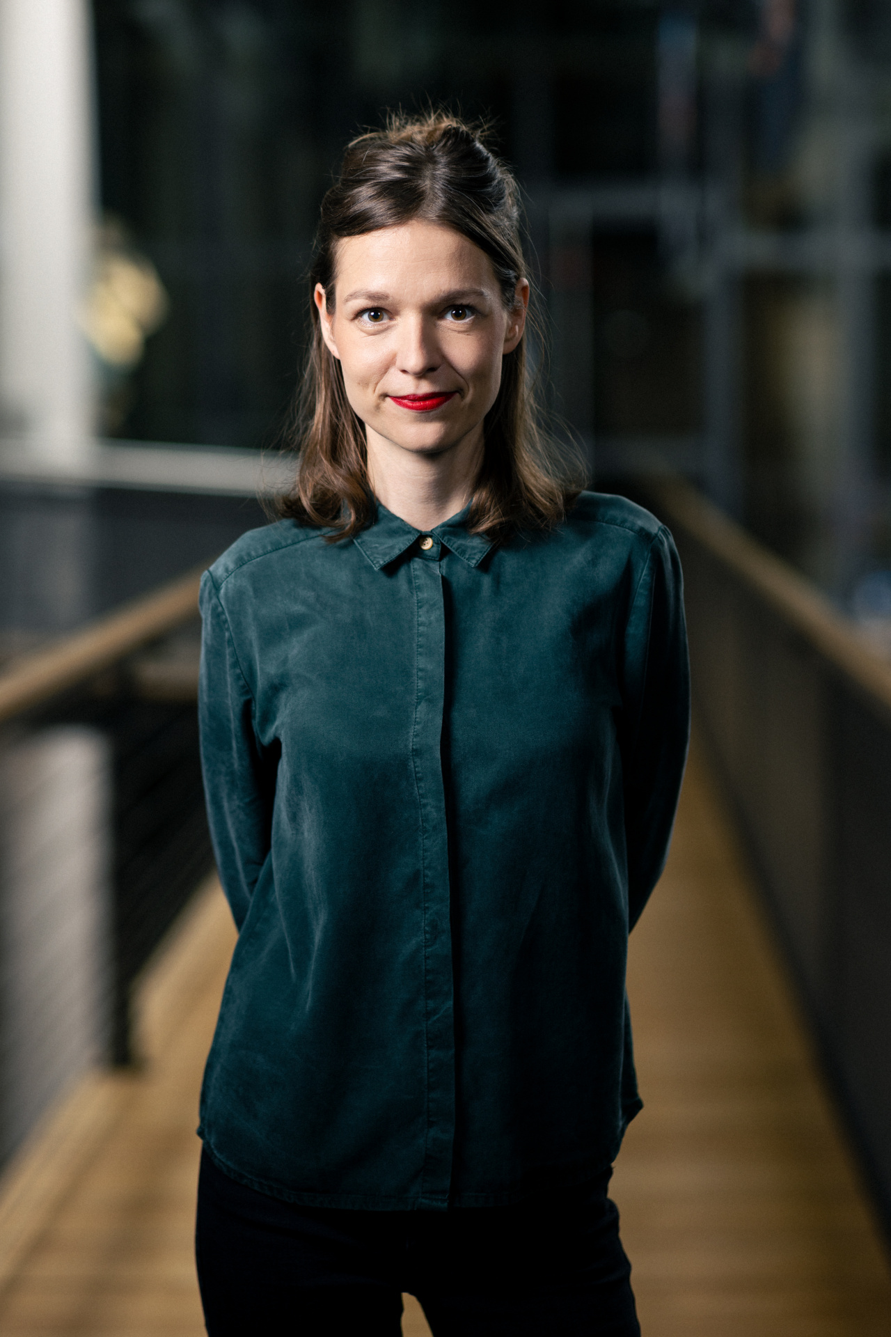 Auf dem Bild ist eine junge Frau mit einer grünen Bluse zu sehen. 