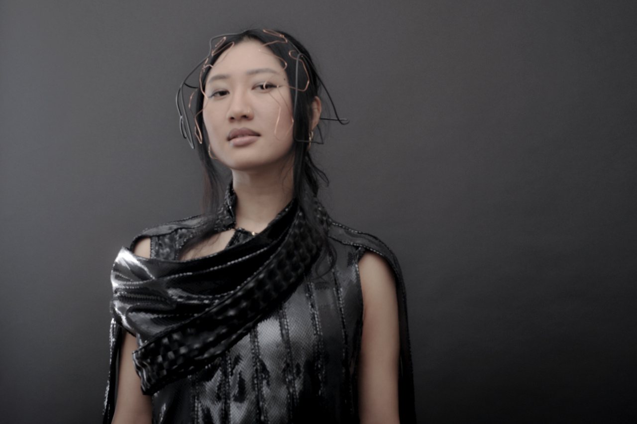 Eine asiatisch gelesene junge Frau vor grauem Hintergrund