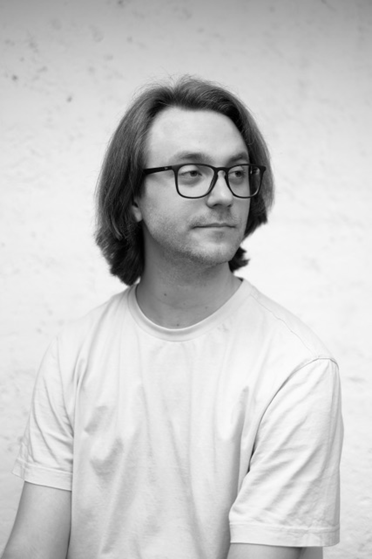 Junger Mann mit Brille, der über seine linke Schulter blickt.