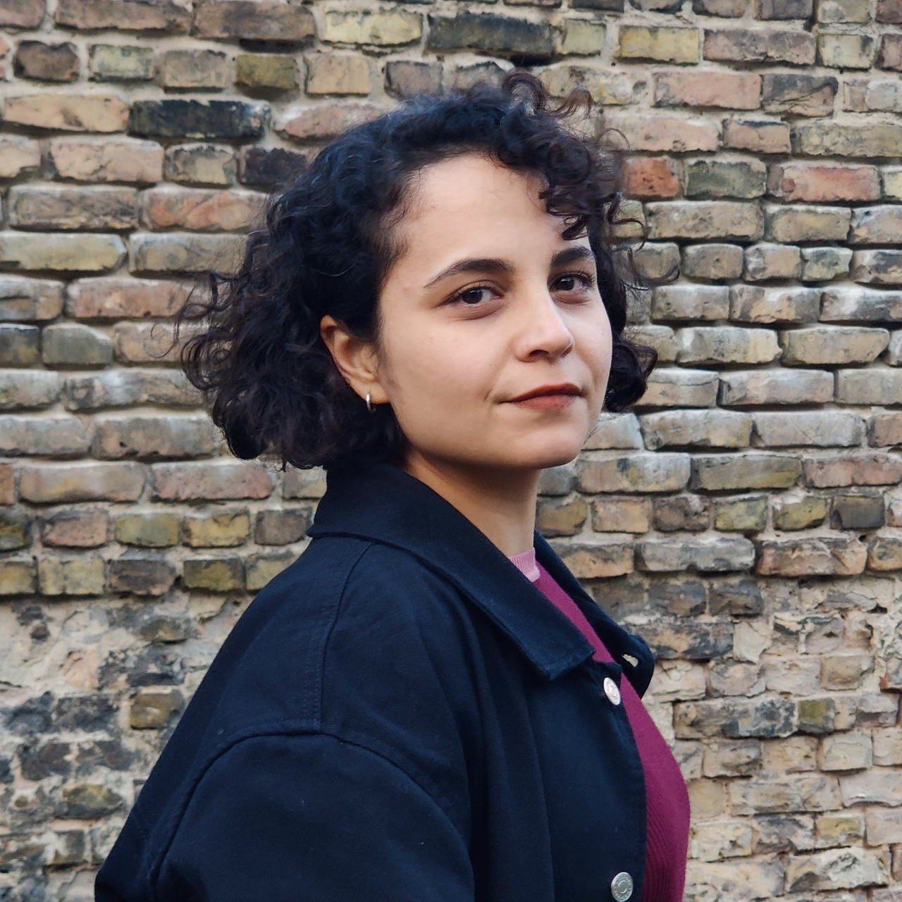Portrait of a woman with black curls and a purple top.