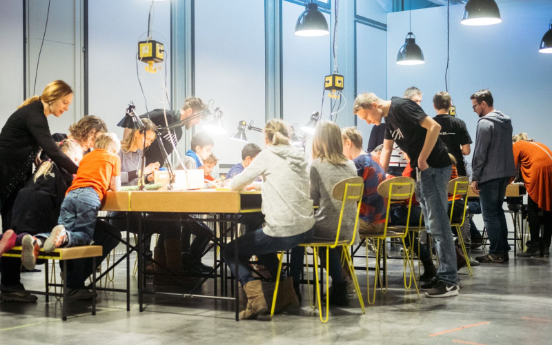 Menschen sitzen an einem erleuchteten Tisch und arbeiten gemeinsam