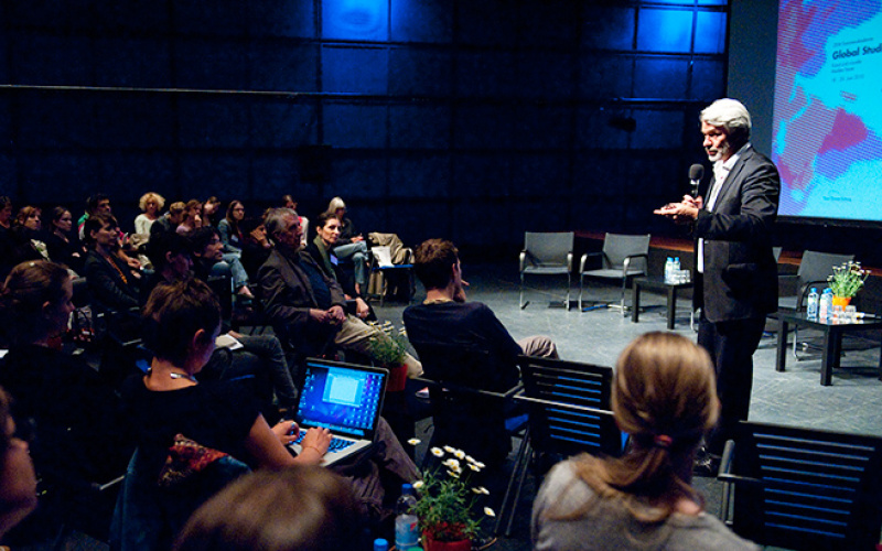A man is giving a speach in front of a seated audience