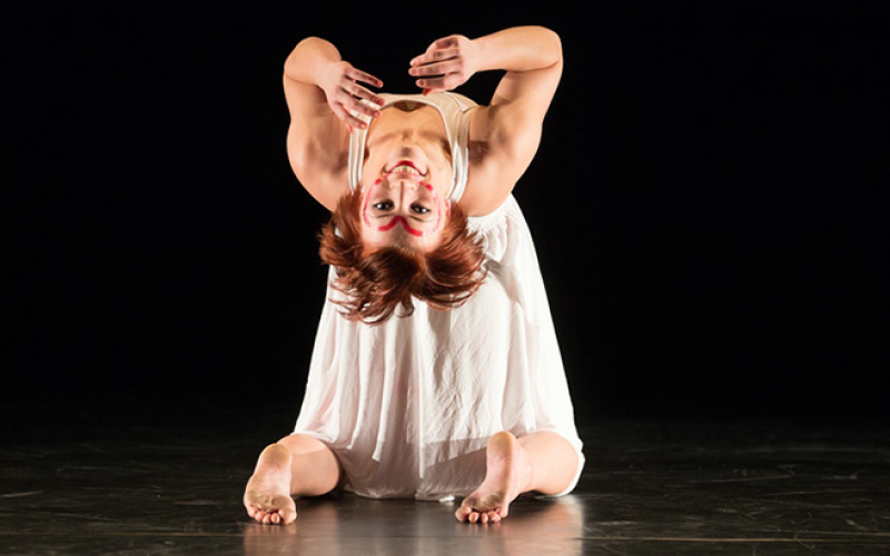 A woman knies down and bends over backwards