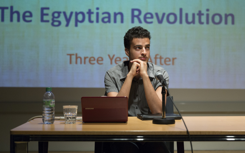 Two man sitting at a table with a laptop and a microphone