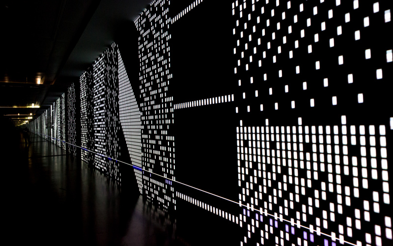 Eine schwarze Leinwand mit gepunkteten LED-Strukturen, die sich scheinbar bis Unendliche erstreckt. 