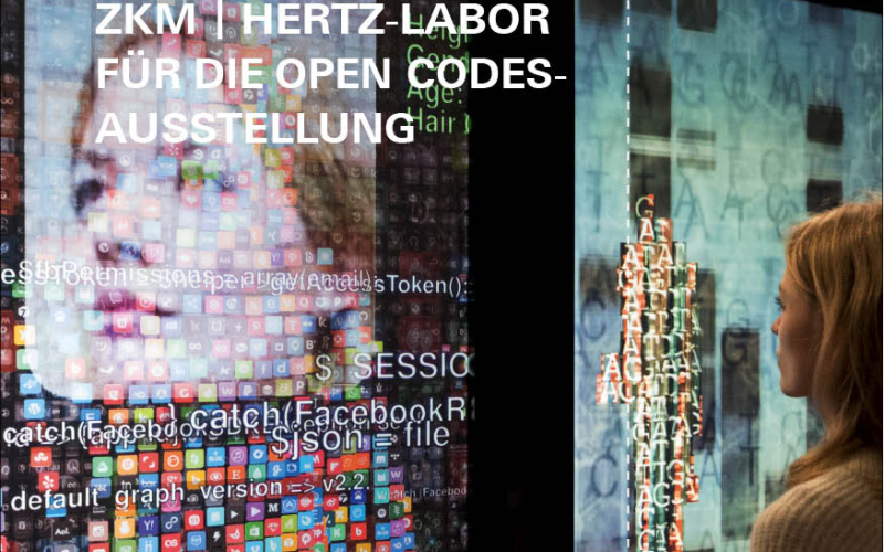 Eine Frau steht vor dem Kunstwerk YOU:R:CODE bestehend aus großen Bildschirmen