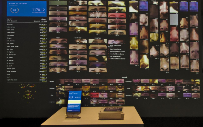 Die Installation zeigt einen Screen mit verschiedenen Gesichtsmerkmalen und einem Display mit einem Smartphone