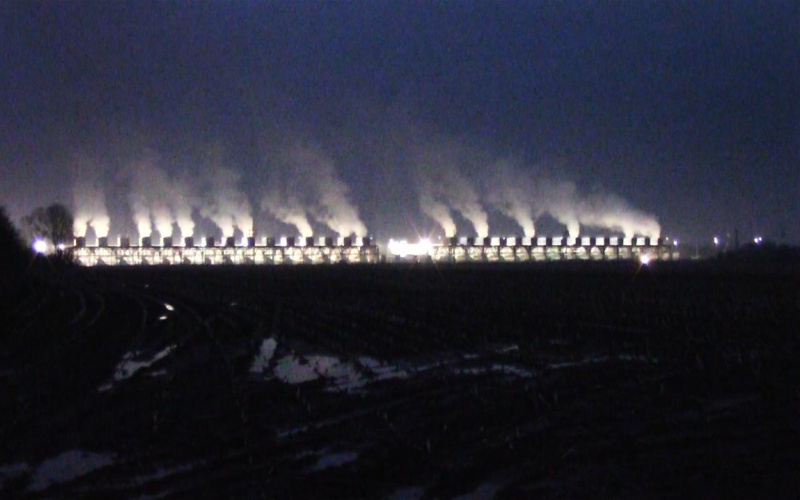 Night photography in dark blue tones with light and smoke on the horizon