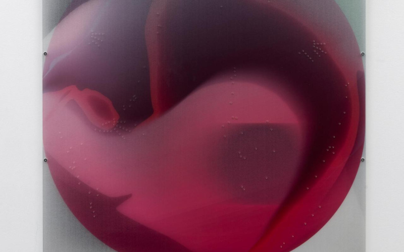 Round, red collage under plexiglass