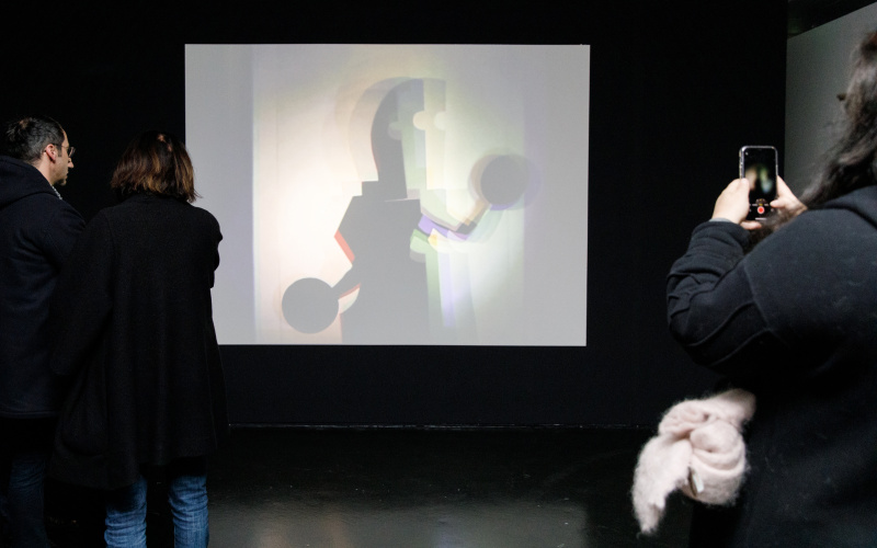 Das Foto zeigt eine große weiße Leinwand auf der eine Bauhaus Figur zu sehen ist.