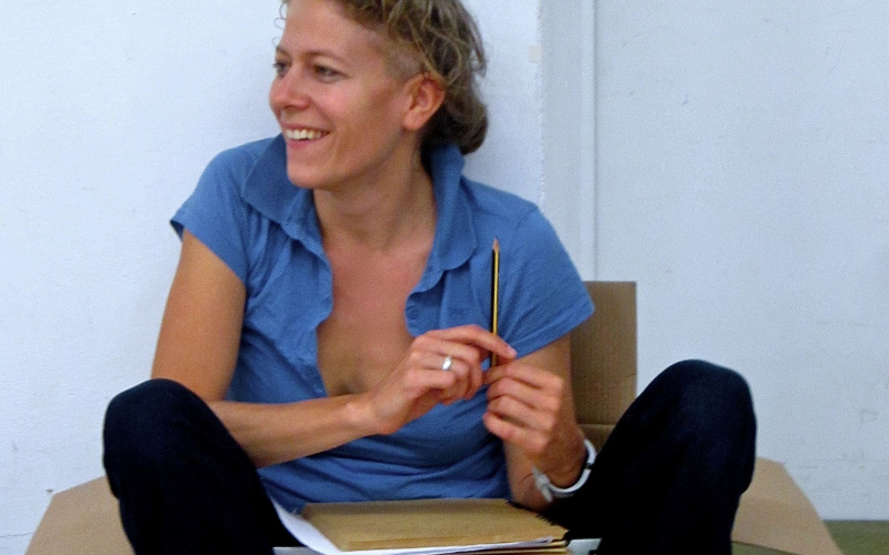  Anja Konjetzky sits casually in a cardboard box and holds a pencil in her hand.
