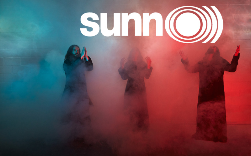 Die drei Musiker der Metalband »Sunn O)))« stehen im blau, weiß und roten Nebel.