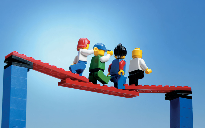 Vier Legofiguren gehen in einer Reihe über eine Brücke.