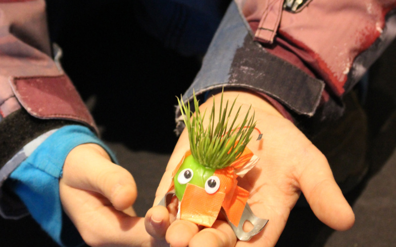 Kinderhände halten einen kleinen E-Käfer mit Kunstrasen als Haaren und Wackelaugen in die Kamera.