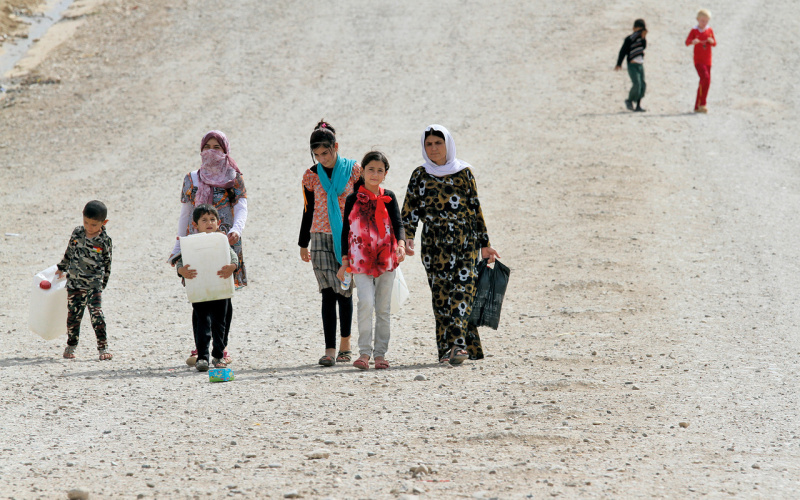 Junge verschleierte Frauen und Kinder auf einer Straße. 