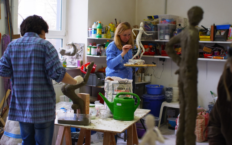Frauen im Atelier arbeiten an schlanken Figuren aus Gips.