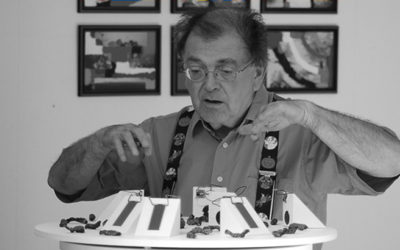 Mann steht mit gehobenen Händen vor Ausstellungsobjekt