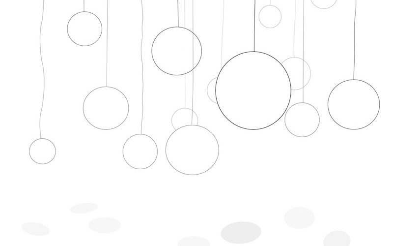 The picture shows a white room in which circles of different sizes are hanging from the ceiling.