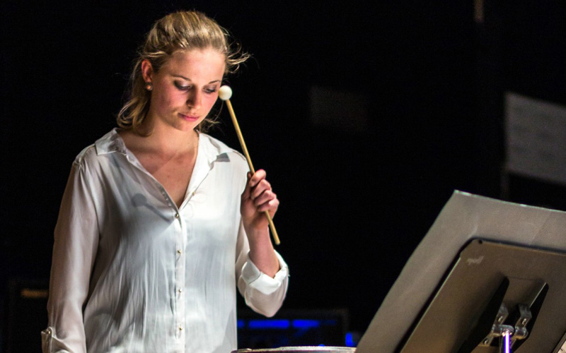  Woman in white shirt plays with drums on percussion.