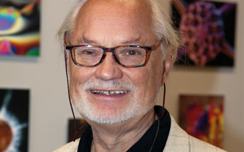 The artist Manfred P. Kage standing in front of hist photographic artworks.