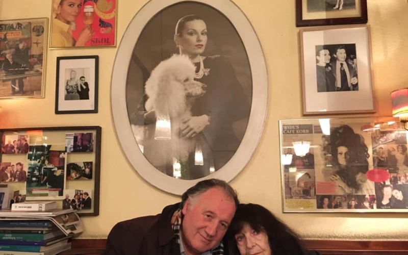 Peter Weibel with Friederike Mayröcker in front of a portrait by Susanne Widl at Café Korb, Vienna 2018.