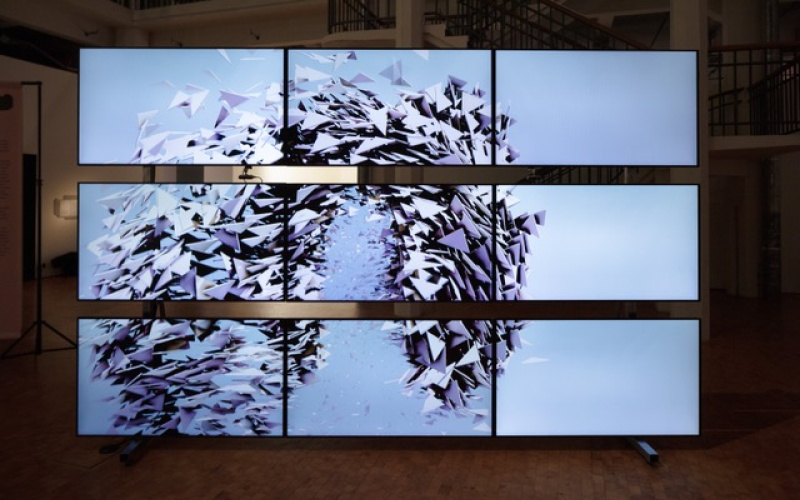 Random International, »Algorithmic Swarm Study (Triptych) / II«, 2021. Auf dem Bild sind neuen Bildschirme, angeordnet zu einem Rechteck, zu sehen. Auf den Bildschirmen ist ein künstlicher Schwarm zu sehen.