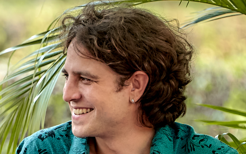 The photo shows a young brown-haired man wearing a green and flowered shirt.